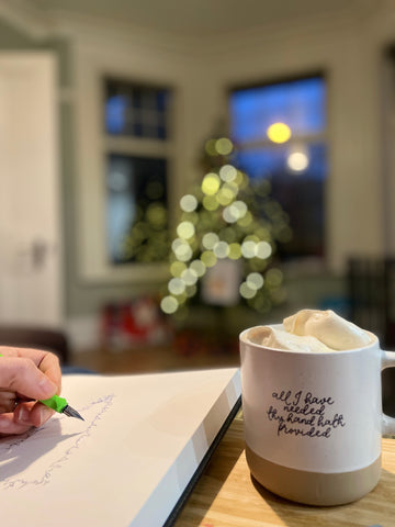 Christian mug at Christmas full of hot chocolate and used by an artist sketching a Christmas tree.