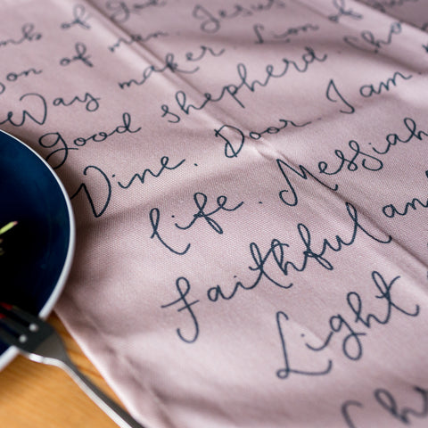 Faithful and true redeemer hand lettered in navy blue on a pink tea towel