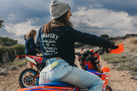 Women enduro rider sitting on a motocross bike with her back turned to the camera