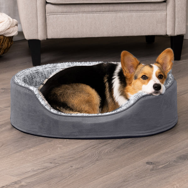 An orange, brown, black and white dog lying in a FurHaven Oval Bed