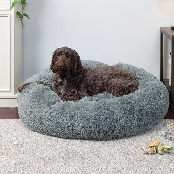 A brown, shaggy dog lying in a FurHaven Calming Cuddler Donut Bed