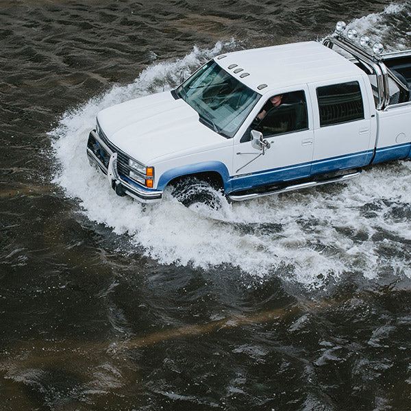 A white and blue SUV drives through deep water, from FurHaven Pet Products