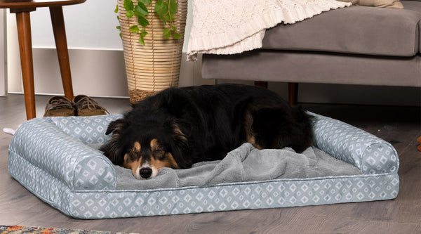 A black and brown dog sleeping on a gray and white FurHaven Diamond Nest Top Pet Bed.