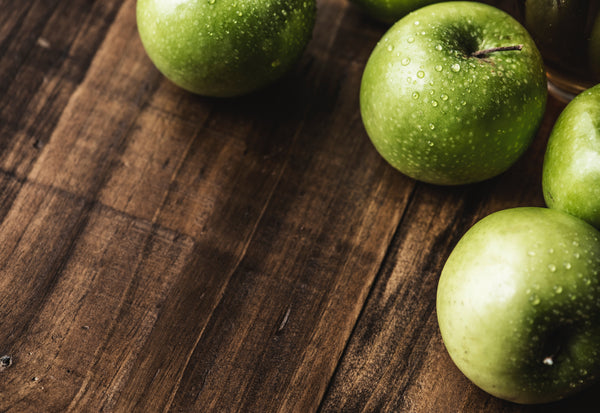 Washed green apples for dogs on a brown cutting board at FurHaven Pet Products