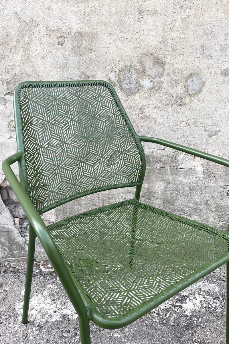 A slight close-up view of the Martini Iron Stackable Bistro Chair in Moss against a concrete backdrop
