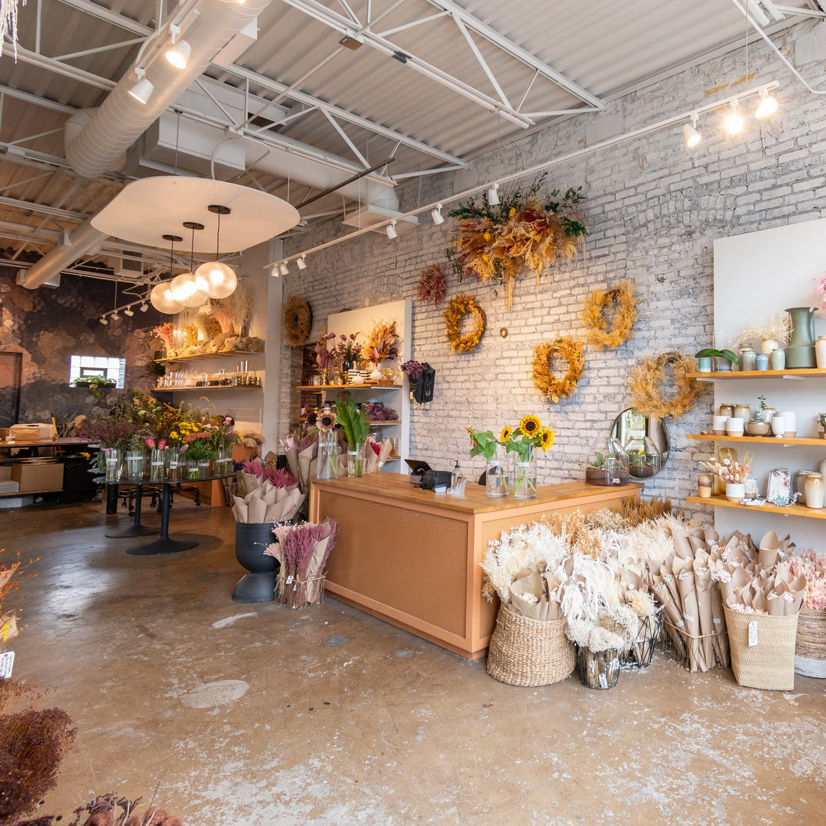 Photo of interior of Sprout Home's floral store, showing white brick wall, wreaths, and cash register