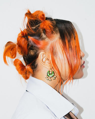 A girl with orange hair looking bold using the colors of Paradyes