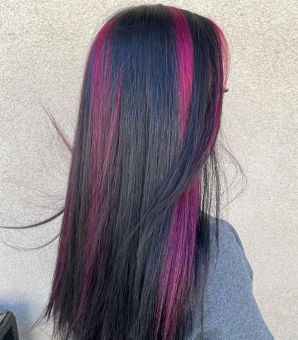 A girl with straight long hair with chunky hair coloring technique with chunks of purple hair color