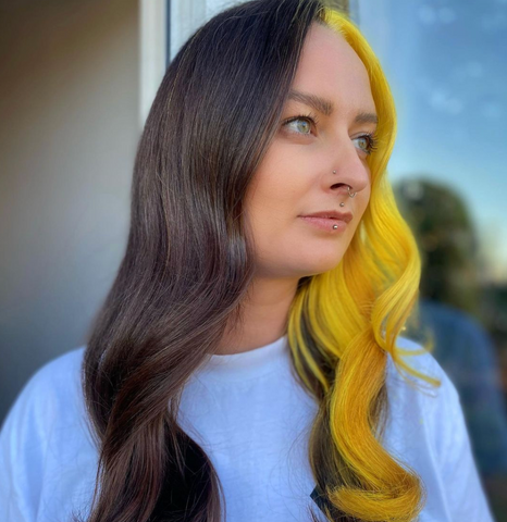 Girl with split dyed hair in yellow and black looking away from the camera