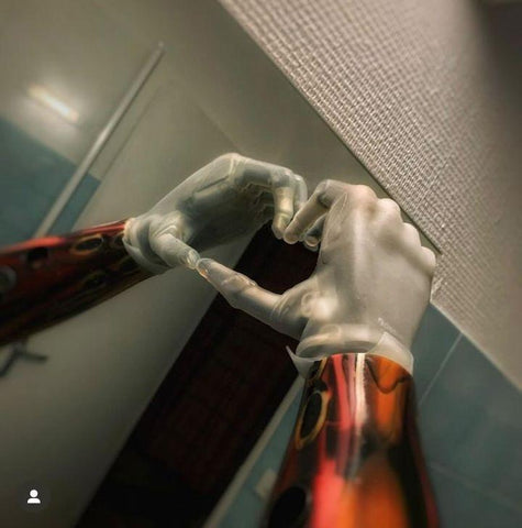 Photo de la main bionique d'Enzo face à un miroir, formant un coeur avec ses doigts