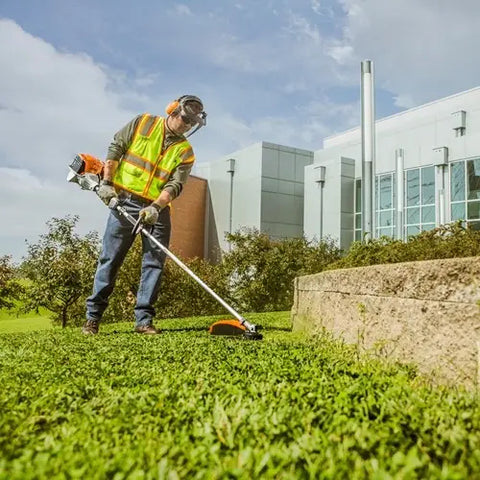 a man using a whipper snipper to trim weeds