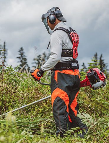 A man using whipper snipper with harness