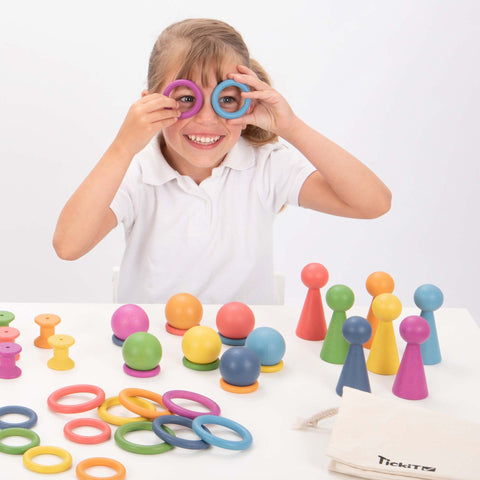 Fille regardant à travers les anneaux en bois TickiT Rainbow