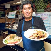 Chef Dean Mishima holding up two dishes while working in a restaurant.