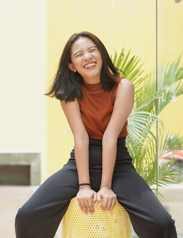 Asian female with healthy, glowing skin sitting and laughing