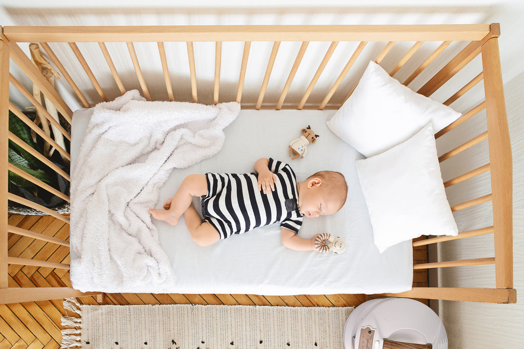 baby in crib with white defender