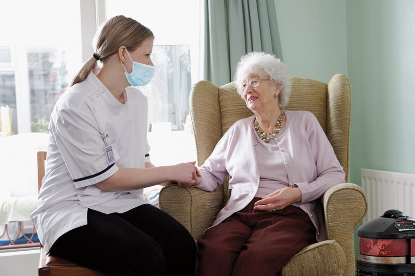 senior nursing home worker helping elderly woman with air purifier running