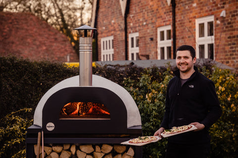 Pizza oven a lit with a Barney holding pizzas that are ready to be cooked
