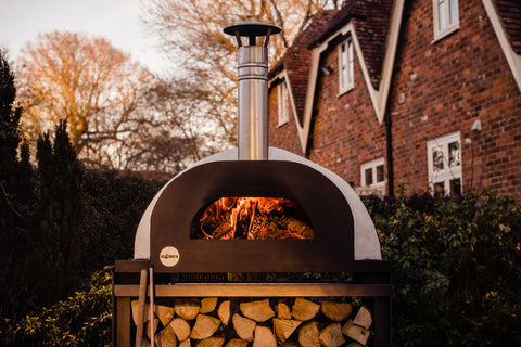 A lit pizza oven in front of a brick house