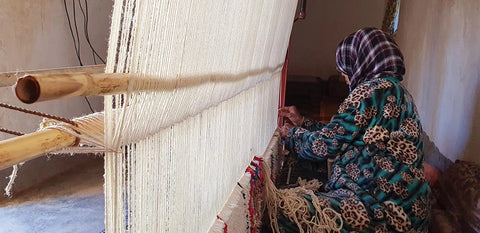 Berber artisans weaving a handmade Moroccan rug in her traditional loom
