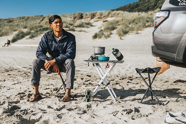 man on beach with PackSeat folding portable stool