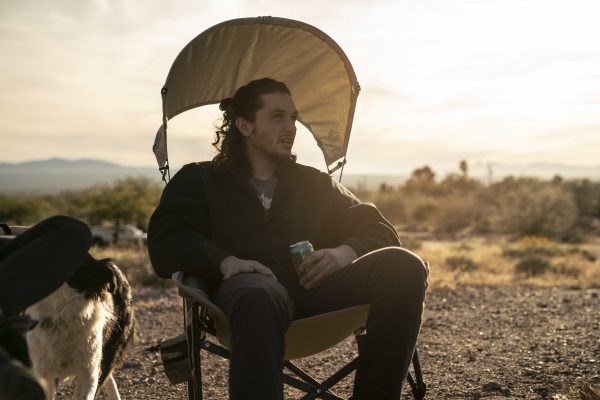 A sports goer sits in his canopy chair staring out into the afternoon sun.