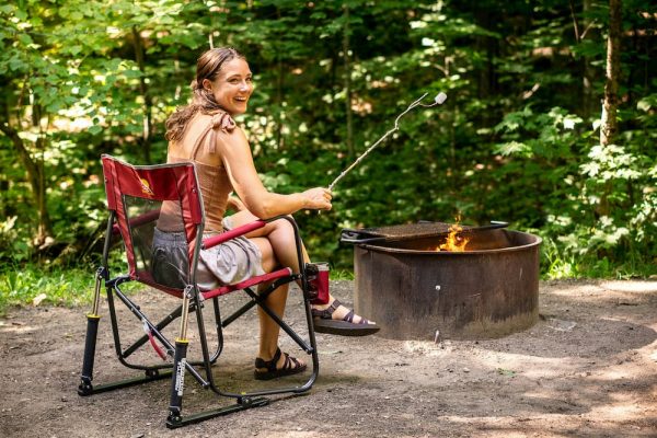 woman sitting in outdoor Freestyle Rocker chair by campfire