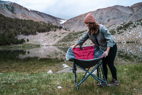 woman unfolding GCI MaxRelax Pod Rocker chair outside in mountains