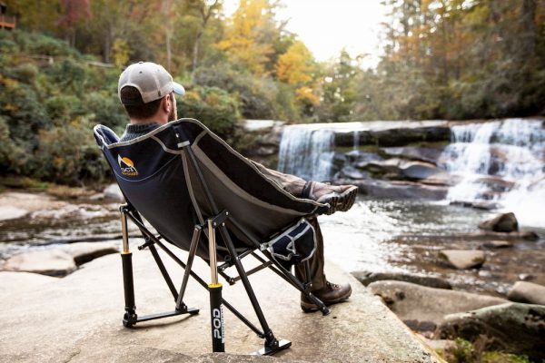 Man sitting in camping chair looking at waterfall 