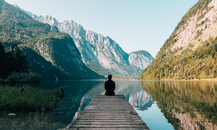 person on a lake looking at the mountains ahead