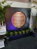 Elysian Copper Wall Fountain with plants and a purple light