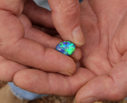 An image of an opal being held in two hands, from the Outback Opal Hunters