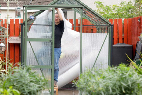 Kate inside greenhouse attaching bubble wrap