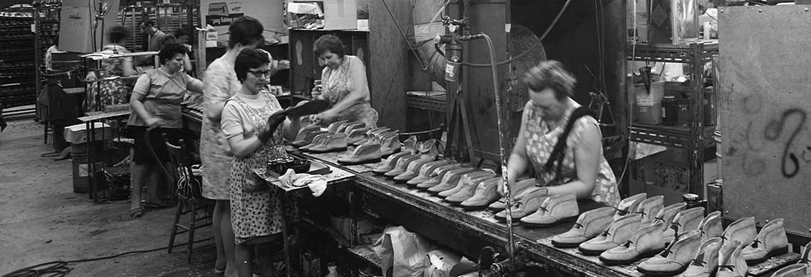 Women working along assembly line in shoe manufacturing plant.