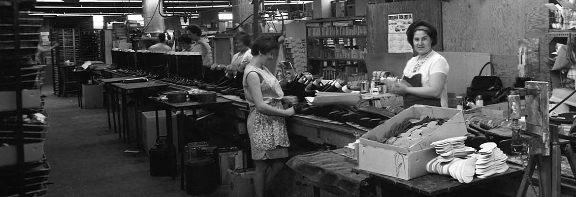 Women working along assembly line in shoe manufacturing plant.