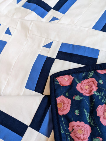 Light blue, dark blue, white quilt with dark blue back with pink flowers