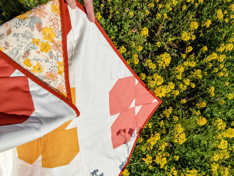 flower quilt in yellow, pink and orange by yellow flowers.