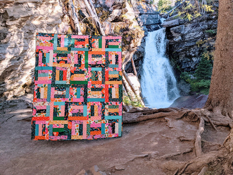 Colorful modern quilt by a waterfall