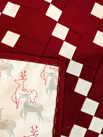 red and white modern snowflake quilt with red and gray reindeer backing