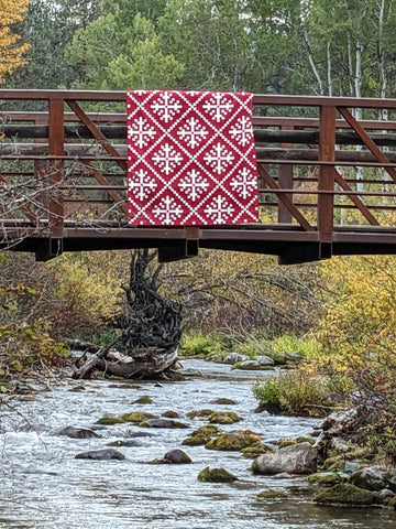 Red and white snowflake quilt hanging on bridge