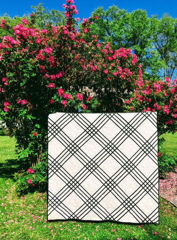 Black and white plaid quilt in front of pink roses