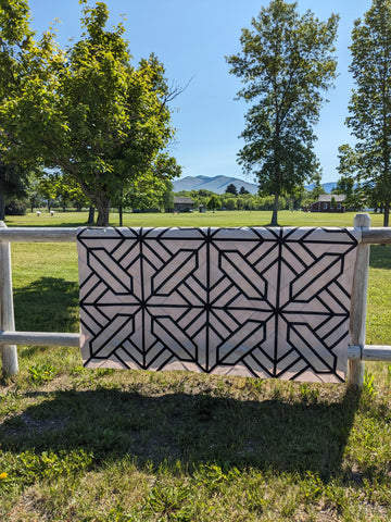 black and tan geometric quilt on fence