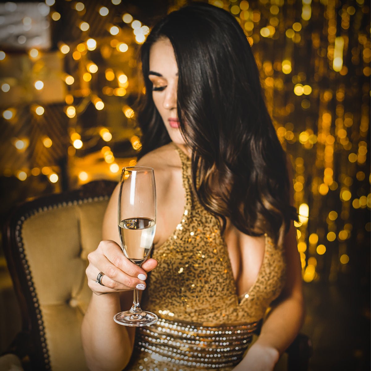Women Holding a Glass Of Champagne In Gold