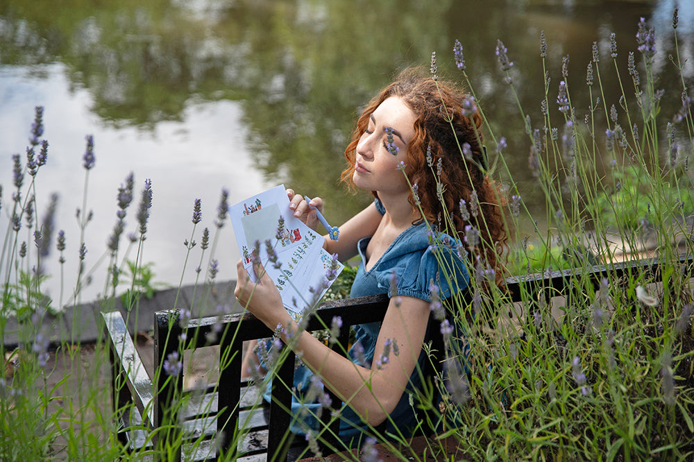 relaxed girl sitting by river writing letters