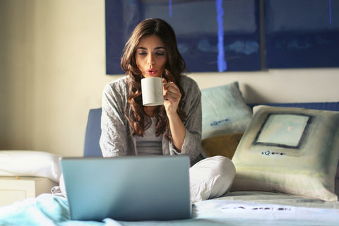 une fille avec une tasse travaillant sur un ordinateur portable 