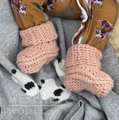 Teeny newborn feet clad in cozy avocado pink booties hand crocheted with our cormo dk yarn