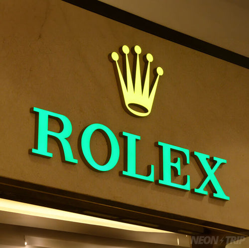 Neontrip 3D frontbeleuchtetes Leuchtschild mit dem Rolex-Logo, bestehend aus einer Krone und dem Schriftzug 'Rolex', angebracht an einer Wand, vermutlich als Ladenbeschilderung für einen hochwertigen Juwelier auf der Königsallee in Düsseldorf.