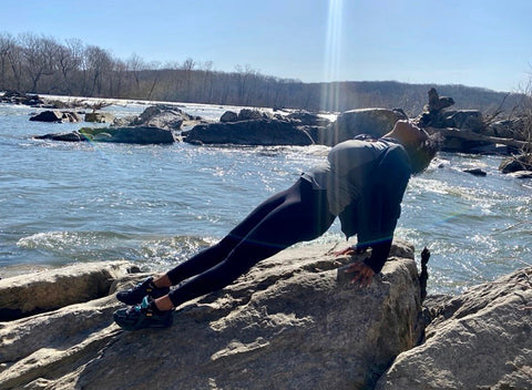 Woman doing yoga pose on rocks in a lake - TraveLoveGo TraveLover TraveLove Love Travel