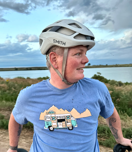 Man with bike helmet wearing blue shirt with image of van and mountains