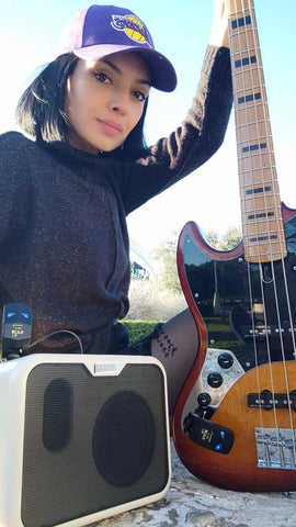 A female musician confidently holding a bass guitar connected to CFG's CF-80 wireless system, showcasing the freedom and ease of playing without cords.